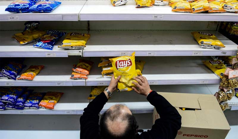 Un empleado de supermercado coloca un paquete de comida con las nuevas etiquetas conformes a la nueva normativa, el 20 de junio de 2016 en Santiago. Foto: AFP.
